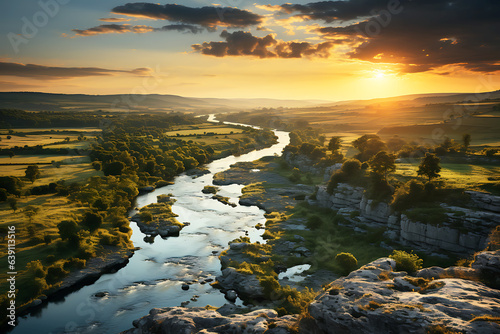A drone view of the valley where the river flows between picturesque meadows and rocky shores. The sun is visible above the horizon