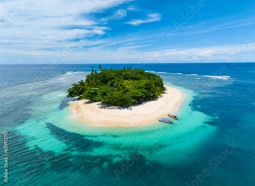 San Victor Island with white sand beach under blue skies and clouds. Turquoise water atoll and coral reefs. Mindanao, Philippines. Summer and travel concept.