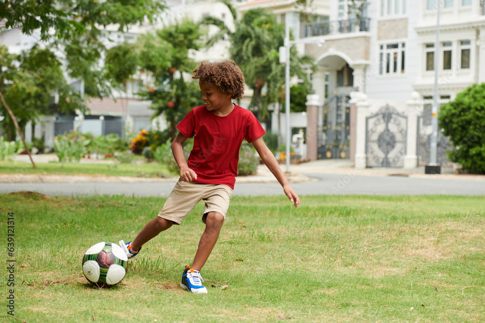 Talented active kid playing soccer on backyard