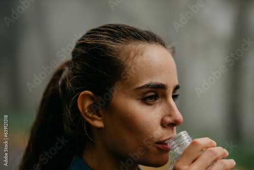 A female runner is drinking water. Close up