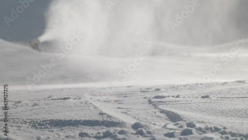 Detail shot of ski tracks in fresh snow; active snow machine in back out of focus
