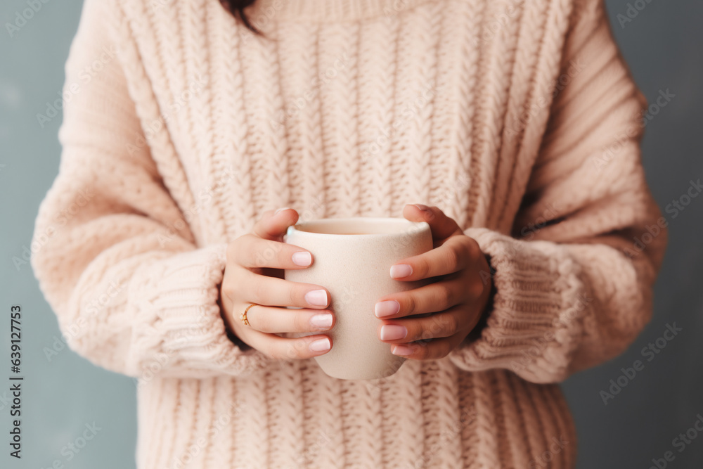 close up of woman in a cosy warm sweater holding a cup of coffee