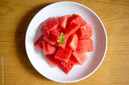 Freshly sliced watermelon on a white plate with a wood pattern background