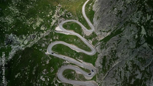Slow aerial climb up a winding road to the Grimselpass in the Swiss Alps. Taken from a drone at high altitude, sunny day