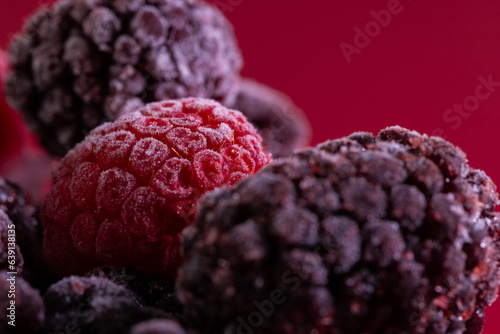 Micro close up of frozen raspberries with copy space on red background