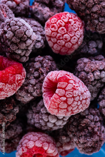 Micro close up of frozen raspberries with copy space on blue background