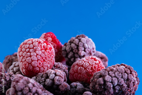 Micro close up of frozen raspberries with copy space on blue background