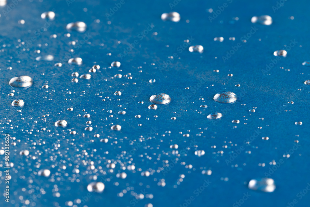 Micro close up of water drops with copy space on blue background