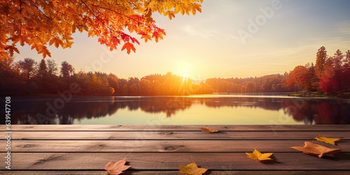 Fall serenity. Tranquil day by lake. Rustic beauty of autumn with wooden table. Sunset glow amidst fall foliage. Lakeside escape © Bussakon