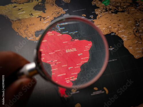 Hand holding magnifying glass and focus to BRAZIL map