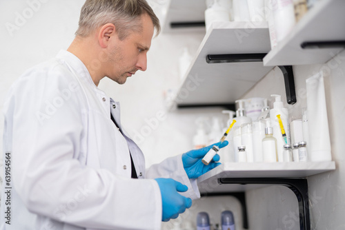 Wallpaper Mural man doctor, cosmetologist  holds a syringe with medicine in his hands Torontodigital.ca