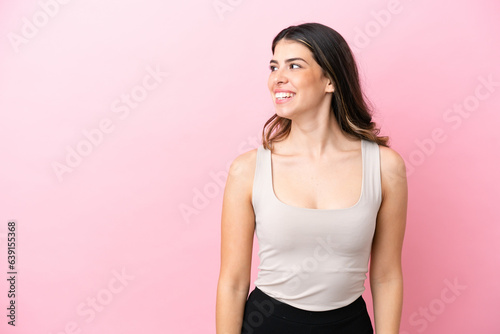 Young Italian woman isolated on pink background looking to the side and smiling