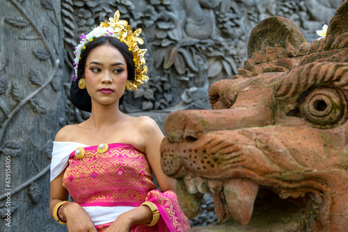 Fotografie Balinese female sitting calmly before large tigger sculpture