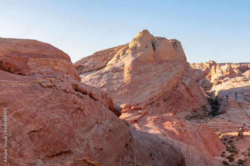 Panoramic sunrise view of arid landscape with striated red and white rock formations along the White Domes Hiking Trail in Valley of Fire State Park in Mojave desert, Overton, Nevada, USA. Road trip