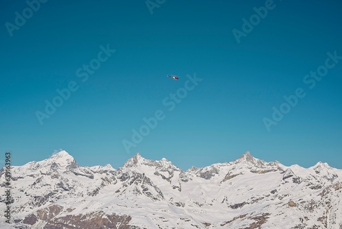 helicopter flying over snow covered mountains