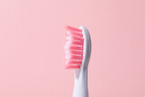 Pink electric toothbrush on pink background, close up