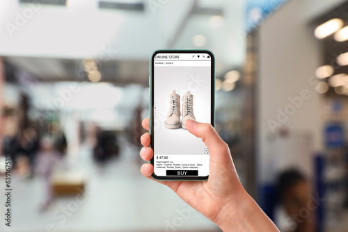 Woman visiting shop to take ordered boots indoors, closeup. Online store website on device screen