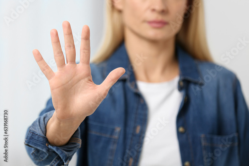 Woman showing stop gesture on blurred background, closeup
