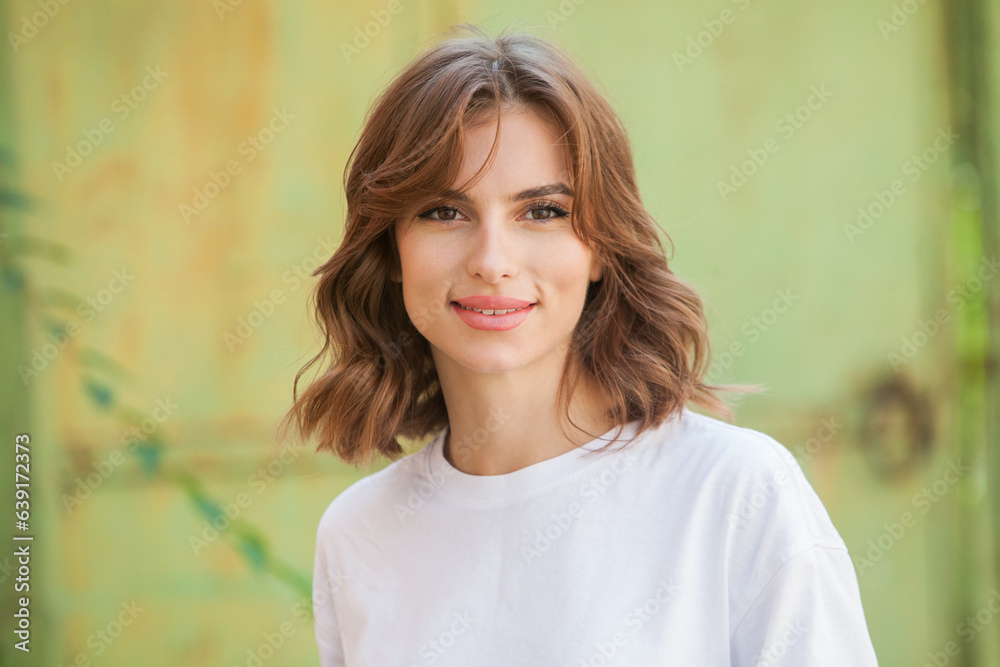 Beautiful young brunette girl in a black T-shirt and blue jeans posing in an urban context Beautiful young brunette girl in a black T-shirt and blue jeans posing in an urban context