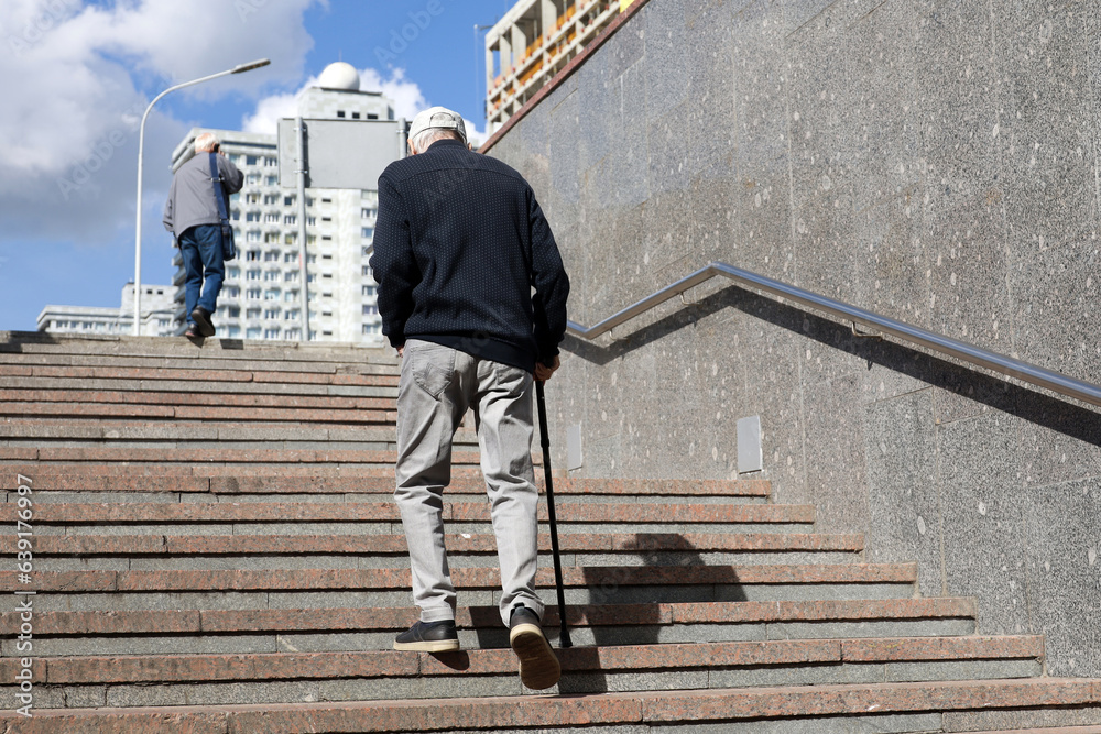 Man Limping Old man with walking cane climbing stairs on city street. Concept for ...