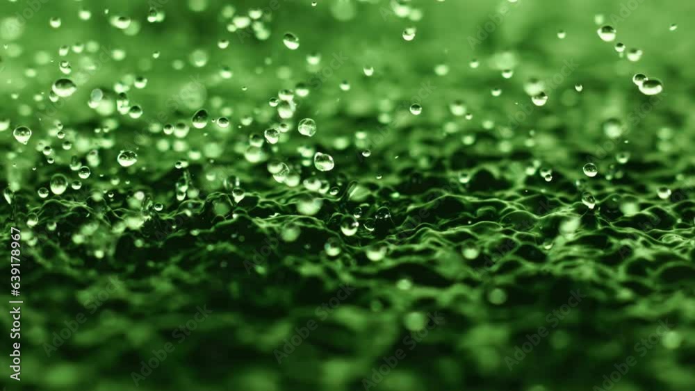 Macro close up super slow motion 1000 fps. Splash drops liquid in green color.Splashes water drops liquid when surface water is vibration.Wave and drops in green background.Crystal particle abstract Macro close up super slow motion 1000 fps. Splash drops liquid in green color.Splashes water drops liquid when surface water is vibration.Wave and drops in green background.Crystal particle abstract