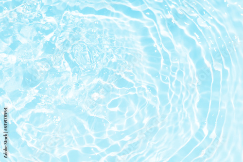 Blue water with ripples on the surface. Defocus blurred transparent blue colored clear calm water surface texture with splashes and bubbles. Water waves with shining pattern texture background.