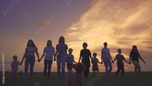large friendly community family silhouette walk in the park. friendly family holding hands walking in nature in the park. happy family kid concept. silhouette large group people holding hands dream
