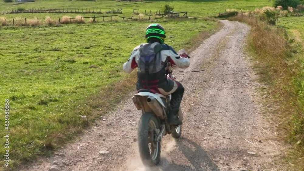 aerial shot of a motocross rider on a journey on a dirt and dusty country road driving fast and exploring beautiful nature while racing chased by the drone. aerial shot of a motocross rider on a journey on a dirt and dusty country road driving fast and exploring beautiful nature while racing chased by the drone.