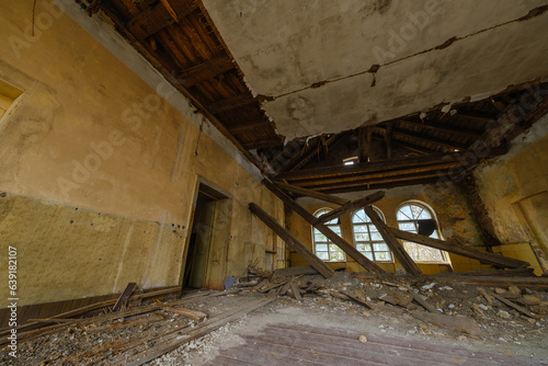 Spacious old room with weathered walls and big dirty windows in dilapidated building during daytime