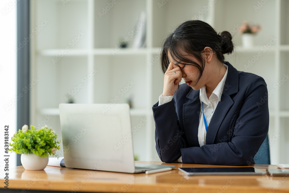 Young Asian businesswoman tired from working long hours, stressed, tired of thinking. Ideas for planning, presenting financial reports, investments, business plans, modern concepts online.