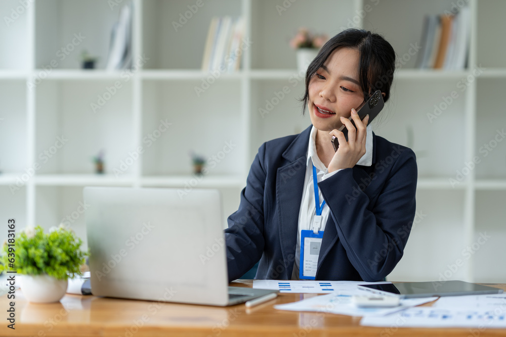 Asian businesswoman using mobile phone to communicate, chat, negotiate, search internet, news, email while working online on laptop computer at office. Asian businesswoman using mobile phone to communicate, chat, negotiate, search internet, news, email while working online on laptop computer at office.