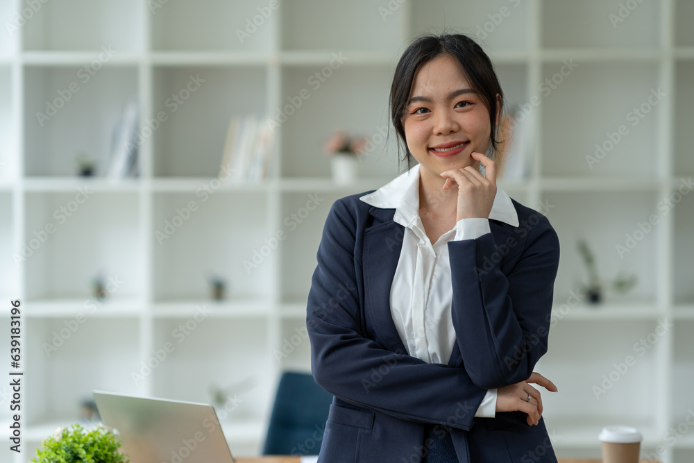 Asian businesswoman standing working with laptop computer, mobile phone, tablet to contact, chat, search internet, news, email, chat while working on finance, marketing, accounting data in office. Asian businesswoman standing working with laptop computer, mobile phone, tablet to contact, chat, search internet, news, email, chat while working on finance, marketing, accounting data in office.