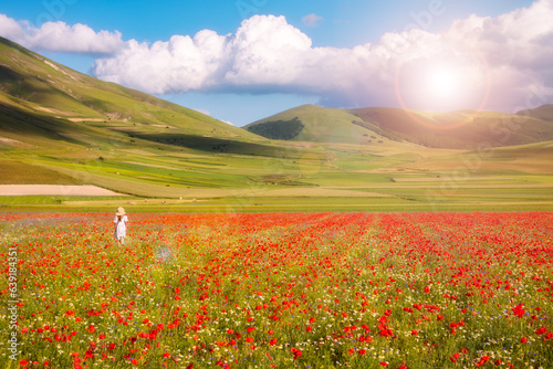 Girl in white dress walking in summer flower field