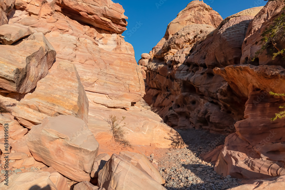 Entrance of the narrow slot canyon along the White Domes Hiking Trail in Valley of Fire State Park in Mojave desert, Nevada, USA. Massive rugged cliffs of striated red and white rock formations