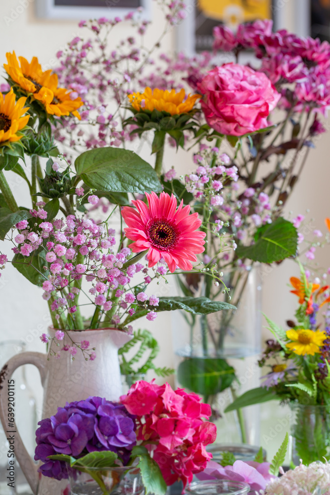 Obraz premium Schöne bunte Blumensträuße in gelb und rosa in Vasen dekorieren ein gemütliches Zuhause