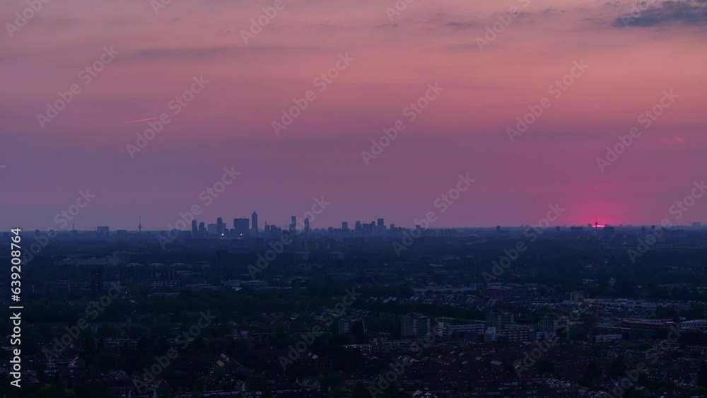 Red sky at sunrise. City homes, businesses and industrial buildings below still in darkness Red sky at sunrise. City homes, businesses and industrial buildings below still in darkness