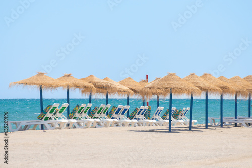 Beautiful sandy beach with palm tree umbrellas and sun loungers