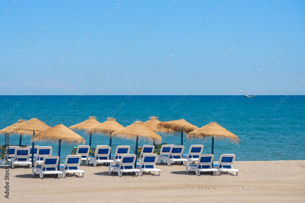 Beautiful sandy beach with palm tree umbrellas and sun loungers
