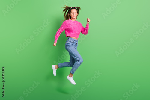 Full length photo of gorgeous lovely woman dressed pink sweater denim pants flying hurry run at sale isolated on green color background