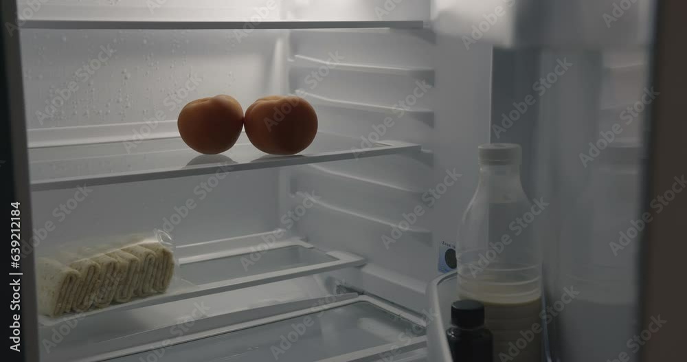 At night, an empty refrigerator opens. The hand takes the last jar from the door