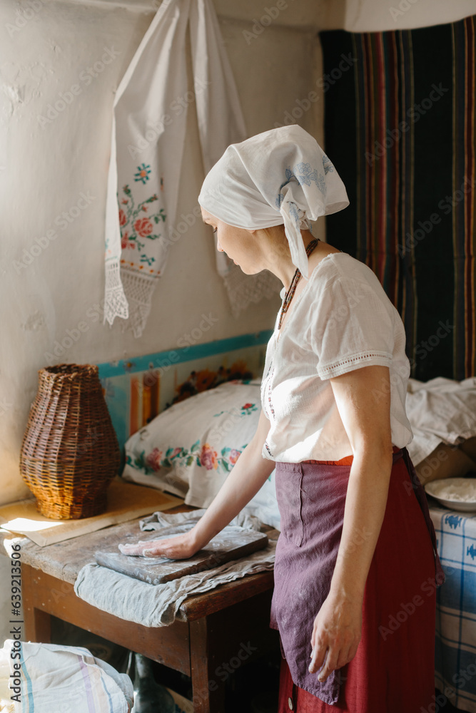 A woman in Ukrainian folk dress prepares dough for baking bread. A woman in Ukrainian folk dress prepares dough for baking bread.