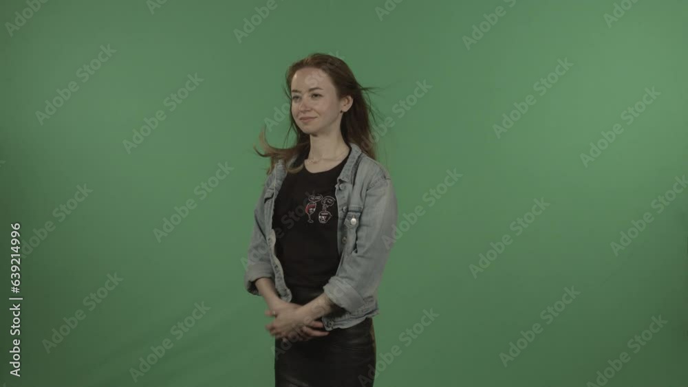 A young, beautiful girl straightens her hair against a green chroma key. A young, beautiful girl straightens her hair against a green chroma key.