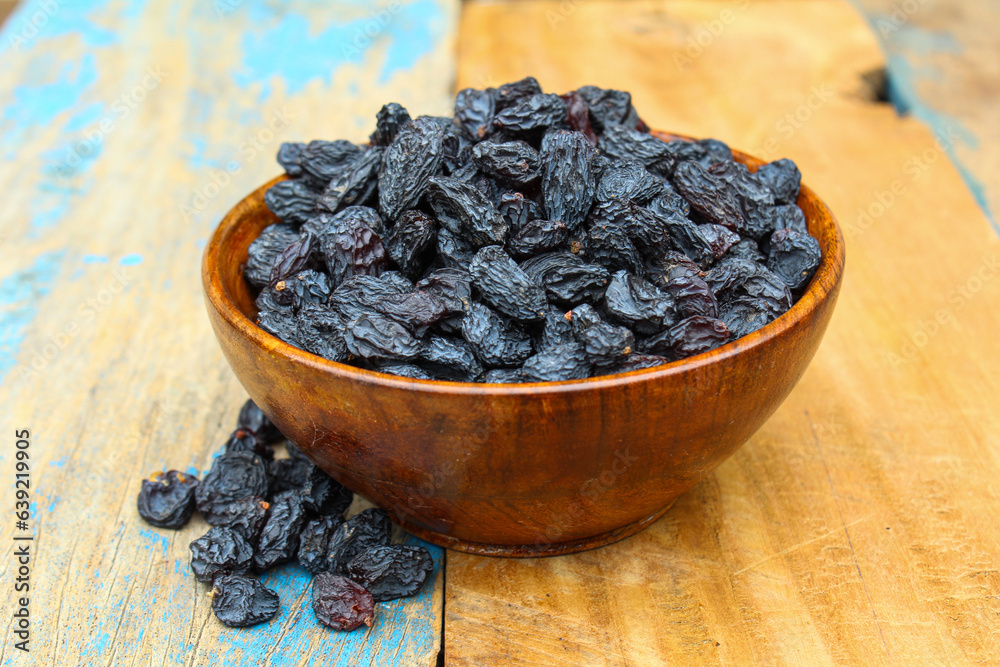 Dried Black raisins in a wooden bowl Dried Black raisins in a wooden bowl
