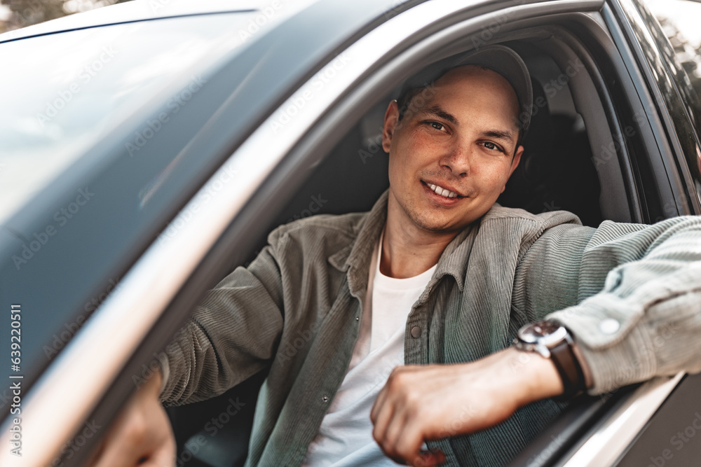 Young smiling man sitting in a car with open window Young smiling man sitting in a car with open window