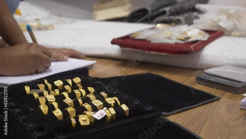 A shopkeeper making counts of hallmarked designer gold jewelry, wedding rings photo