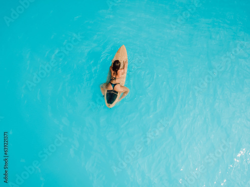 Photography Surfer girl in bikini waiting wave on surfboard in blue ocean
