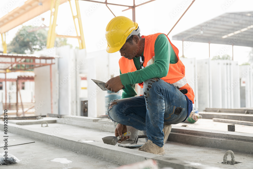 Fototapeta premium Asian male builder worker working at construction site. Male mason working at construction site