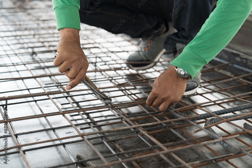 Hands of construction worker fabricating steel reinforcement bar at construction site. Male mason working with steel bar at work site Hands of construction worker fabricating steel reinforcement bar at construction site. Male mason working with steel bar at work site