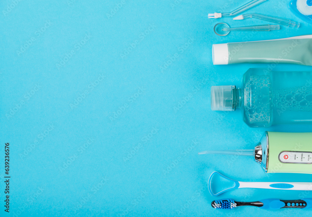 Electronic oral irrigator, toothbrush, paste, dental floss and mouthwash on a blue background. Dental tool for oral hygiene. Electric Interdental Cleaner. Dental water shower. Oral care concept. Electronic oral irrigator, toothbrush, paste, dental floss and mouthwash on a blue background. Dental tool for oral hygiene. Electric Interdental Cleaner. Dental water shower. Oral care concept.