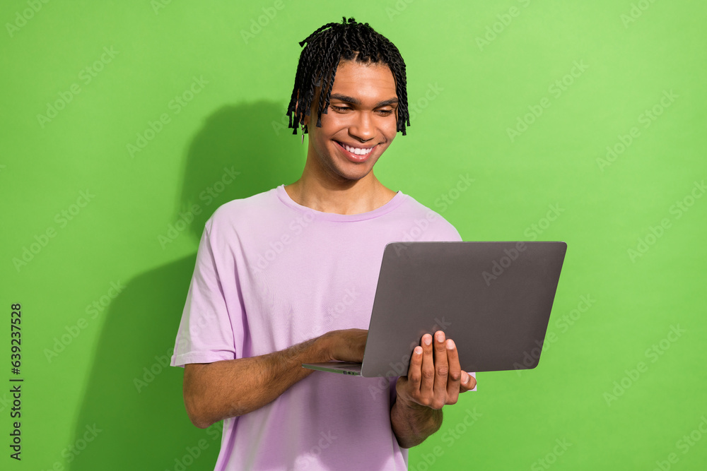 Photo of attractive cheerful person toothy smile use wireless netbook isolated on green color background Photo of attractive cheerful person toothy smile use wireless netbook isolated on green color background